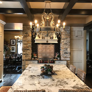 Kitchen Island featuring granite, chandelier, wood beams, custom cabinets and tile